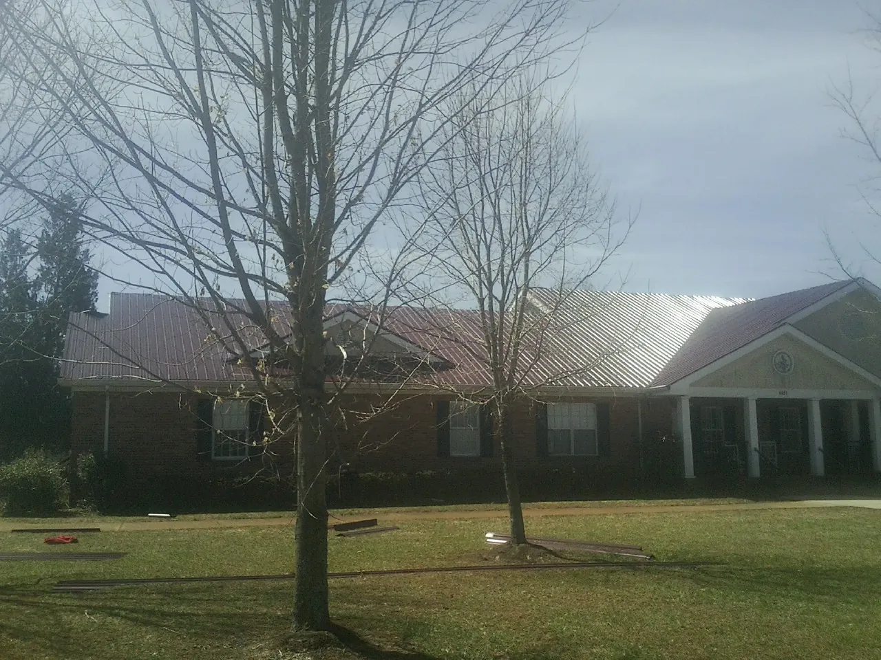 Red metal roof on a brick building seen from the front lawn in Bruno