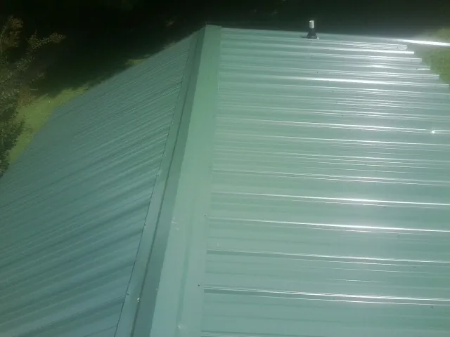 New green metal panels meeting at the ridge of a roof — Flat Roof Repair work by our crew in Bruno
