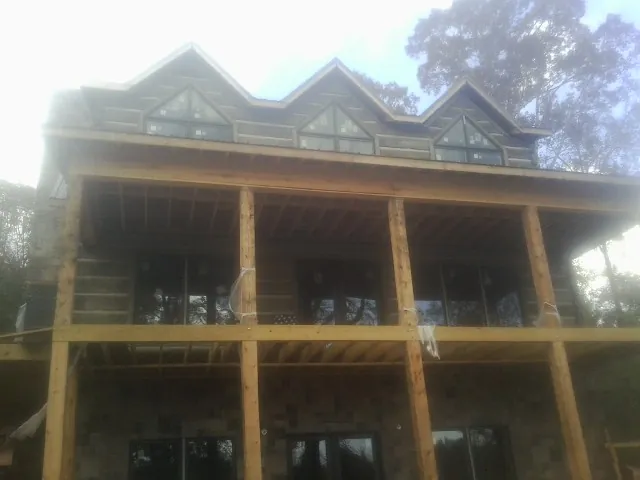 Dormers and porch framing on a large log home under construction — Roof Coating work by our crew in Bruno