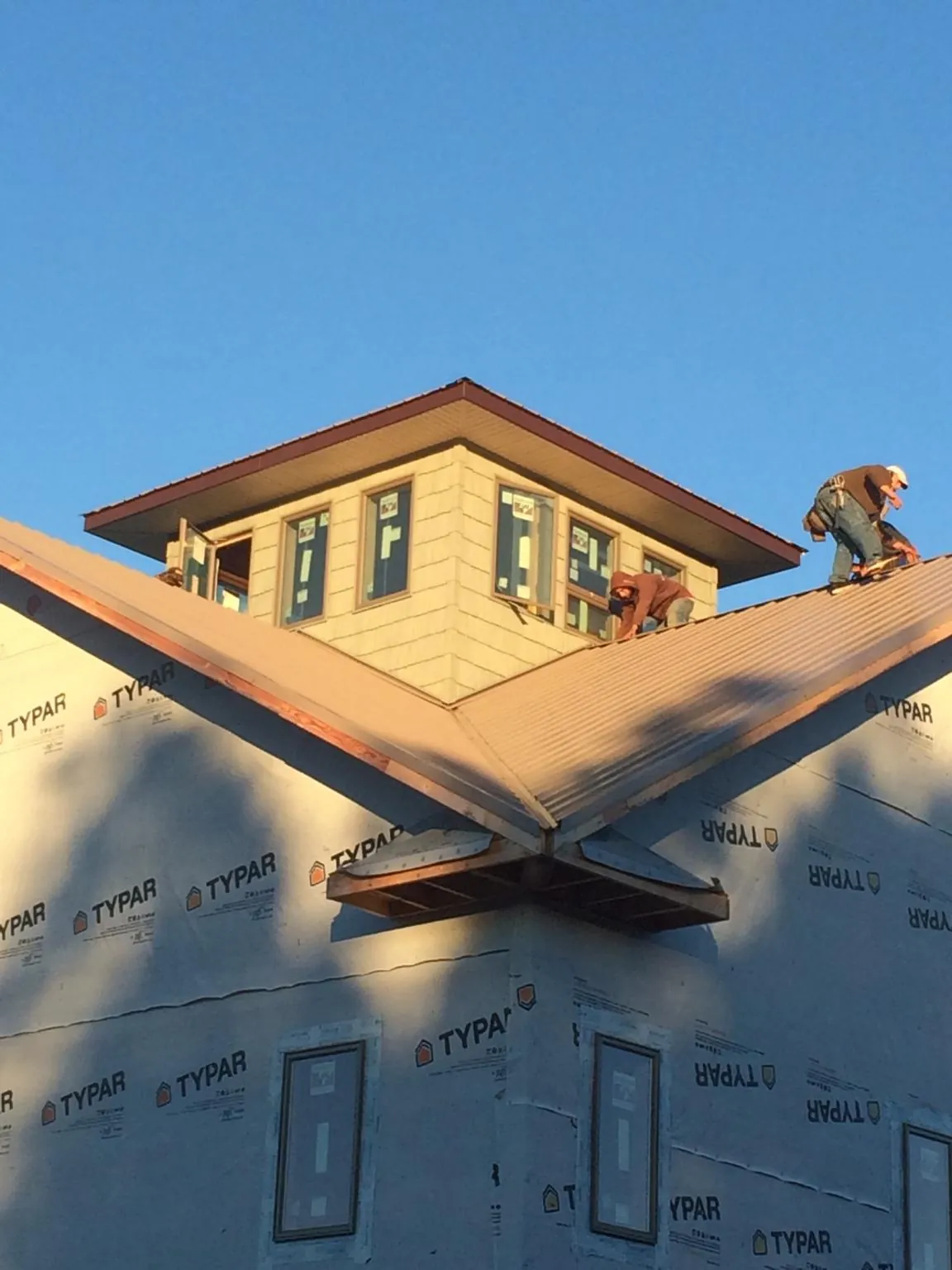Roofers working around a rooftop cupola on a new metal roof at sunset — Roof Waterproofing in Bruno by Roofing Brothers